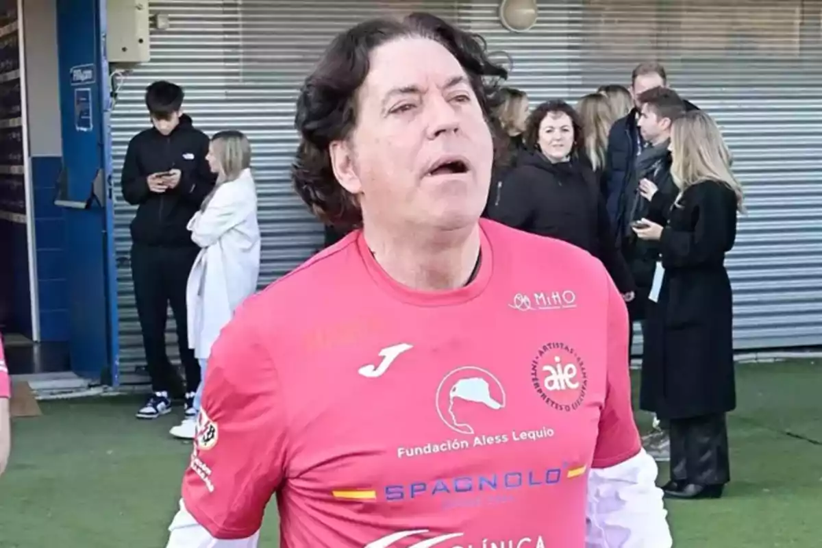 Pipi Estrada amb samarreta rosa de la Fundació Aless Lequio està en un esdeveniment exterior amb diverses persones al fons. Pipi Estrada amb samarreta rosa de la Fundació Aless Lequio està en un esdeveniment exterior amb diverses persones al fons.